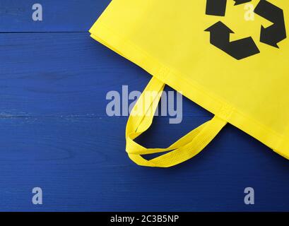 Wiederverwendbarer gelber Viscose-Beutel auf blauem Holzhintergrund, Kunststoff-Abfallreduzierungskonzept Stockfoto
