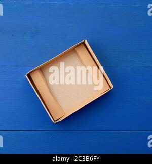 Öffnen Sie die leere braune Kartonschachtel für Transport und Verpackung von Waren auf blauem Holzhintergrund, Draufsicht. Stockfoto