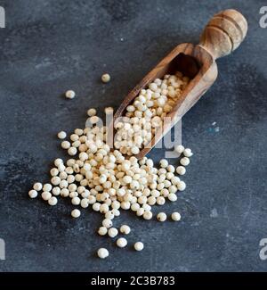 Raw weißen Sorghum Getreide mit einem Löffel auf einer grauen Tabelle Stockfoto