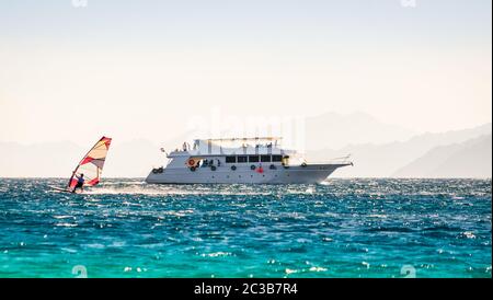 Big Boot und ein Surfer im Meer auf dem Hintergrund einer felsigen Küste in Ägypten Dahab Stockfoto