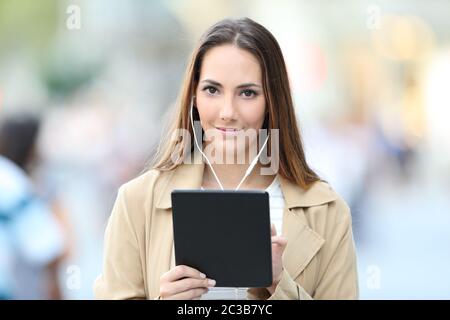 Fronf Blick Porträt einer schweren Mädchen mit Ohrhörer, eine Tablette zu suchen Sie auf der Straße Stockfoto