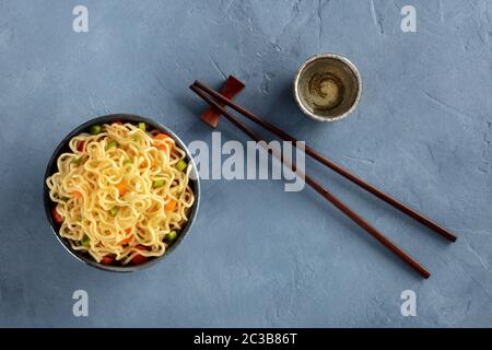 Sofort-Nudeln-Schüssel mit Karotten und Hengsten, Top-Schuss mit Essstäbchen und Sake Stockfoto