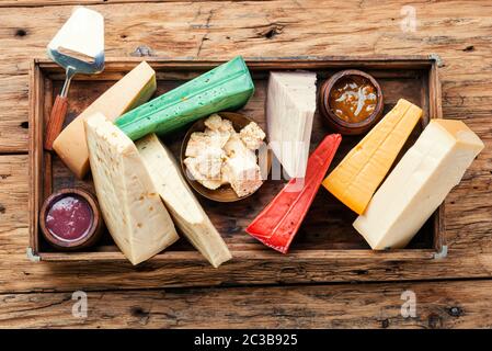 Verschiedene Käsesorten werden auf einem rustikalen Holztisch in der Schachtel serviert Stockfoto