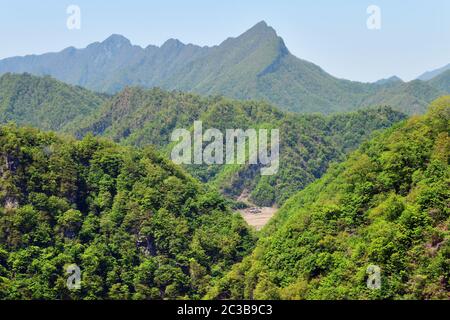 Nordkorea. Tolle Landschaft. Berge mit Bäumen und Dorf im Tal bedeckt Stockfoto