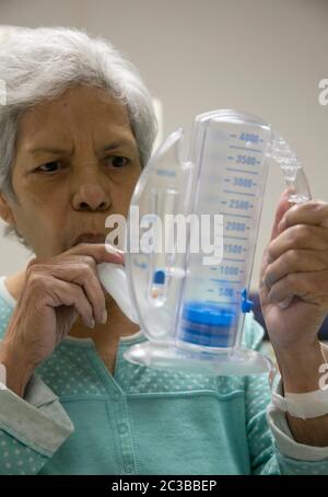 Austin Texas USA, Februar 11 2014: 75-jährige hispanische Frau benutzt ein medizinisches Atemübungsgerät während der Erholung in einem Rehabilitationskrankenhaus. ©Marjorie Kamys Cotera/Daemmrich Photography Stockfoto