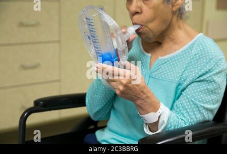 Austin Texas USA, Februar 11 2014: 75-jährige hispanische Frau benutzt ein medizinisches Atemübungsgerät während der Erholung in einem Rehabilitationskrankenhaus. ©Marjorie Kamys Cotera/Daemmrich Photography Stockfoto