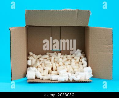 Öffnen rechteckigen braunen Karton mit weißer Schaum Füllung für den Transport von Gütern auf einem blauen Hintergrund Stockfoto