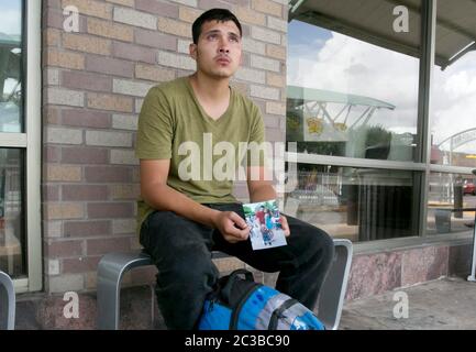 McAllen Texas, USA, Juni 24 2014: US-Staatsbürger Julio Cesar Garcia Duarte zeigt Tränen ein Foto seiner Familie, während er mit Freiwilligen und Mitarbeitern am Busbahnhof McAllen, Texas, spricht, um Informationen über seine guatemaltekische Ehefrau und sein Kind zu erhalten, das er aufspüren möchte. Er hatte Informationen, dass sie an diesem Tag die Grenze von Mexiko in die Vereinigten Staaten mit einem "Kojoten" überquerten. ©Marjorie Kamys Cotera/Daemmrich Photography Stockfoto