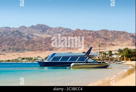 Zwei Boote auf der Brandung auf dem Hintergrund des Strandes mit Palmen und hohen felsigen Bergen in Egy Stockfoto