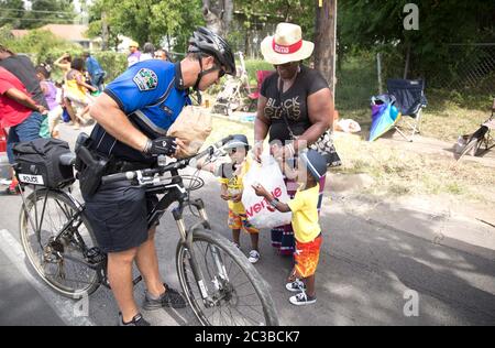 Juneteenth Parade--Austin, Texas, USA, Juni 21 2014: Austin Police Department Bike Patrol Officer interagiert mit kleinen Kindern und ihrer Großmutter auf der Route der jährlichen Juneteenth Parade durch Austin, Teil einer ganztägigen Feier. Juneteenth, auch bekannt als „Tag der Freiheit“ oder „Emanzipationstag“, feiert das Ende der Sklaverei in den Vereinigten Staaten am Ende des Bürgerkriegs oder des Krieges zwischen den Staaten. ©Marjorie Kamys Cotera/Daemmrich Photography Stockfoto