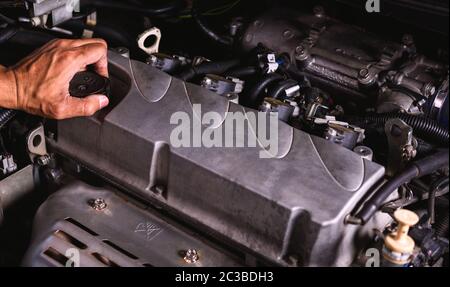 Hand der Automechaniker Techniker Service Engine und das Motoröl Deckel auf Auto öffnen in einer Garage. Stockfoto