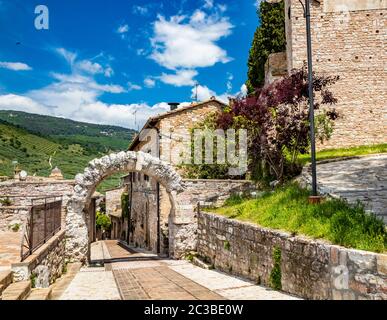 Die gepflasterten Gassen des Dorfes und die Stein- und Ziegelhäuser. Ein römischer Steinbogen. Die gepflasterten Straßen. In Spello, Provinz Perugia, Umbrien, Italien Stockfoto