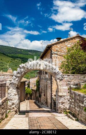 Die gepflasterten Gassen des Dorfes und die Stein- und Ziegelhäuser. Ein römischer Steinbogen. Die gepflasterten Straßen. In Spello, Provinz Perugia, Umbrien, Italien Stockfoto