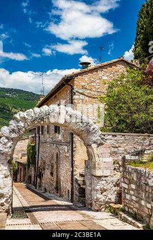 Die gepflasterten Gassen des Dorfes und die Stein- und Ziegelhäuser. Ein römischer Steinbogen. Die gepflasterten Straßen. In Spello, Provinz Perugia, Umbrien, Italien Stockfoto