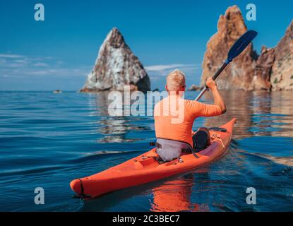 Kajak. Sportler Kajakmann genießt Abenteuer auf ruhigen Meer mit blauem Wasser. Freizeitaktivitäten auf dem ruhigen blauen Wasser. Das Konzept eines aktiven und gesunden Stockfoto