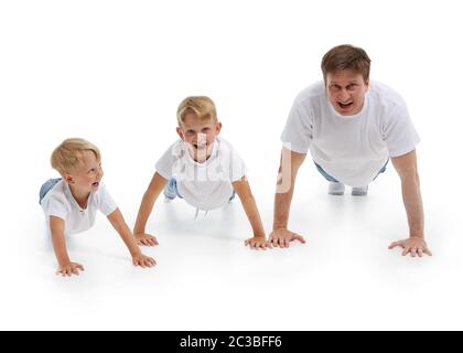 Vater mit zwei Söhnen. Junger Mann mit Kindern isoliert auf einem weißen Hintergrund machen Gymnastik Übungen. Liegestütze. Elternschaft, Konzept der gesunden l Stockfoto