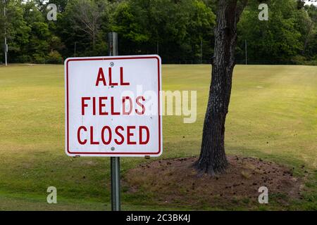 Leere grüne Gras Sportplatz hinter einem Schild sagen, alle Felder geschlossen, Sportausscheiden durch Coronavirus, horizontaler Aspekt Stockfoto