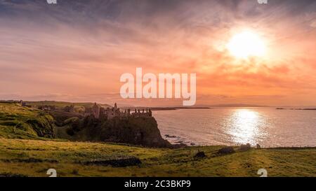 Ruinierte das mittelalterliche Dunluce Castle auf der Klippe in Bushmills, Nordirland bei Sonnenuntergang. Drehort beliebter TV-Serien Stockfoto