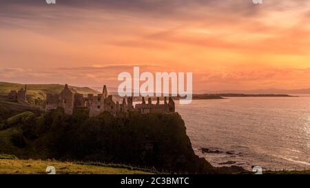 Ruinierte das mittelalterliche Dunluce Castle auf der Klippe in Bushmills, Nordirland bei Sonnenuntergang. Drehort beliebter TV-Serien Stockfoto