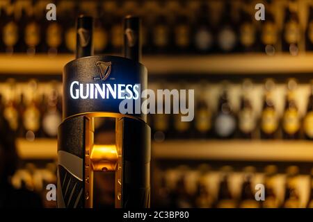 Selektiver Fokus auf Guinness Hahn mit verschwommener Wand aus Flaschen Stockfoto