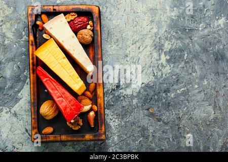 Küche mit verschiedenen Arten von köstlichen Käse auf dem Tisch. Drei Scheiben Käse auf einem hölzernen Küche board Stockfoto