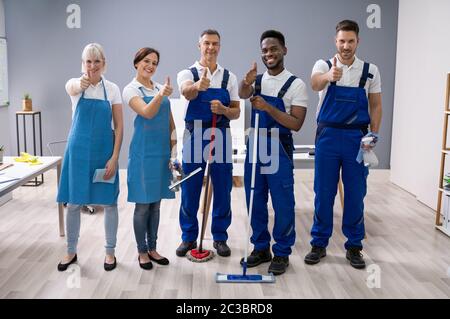 Portrait von Happy Diverse Hausmeister im Büro mit der Reinigung der Ausrüstung zeigen Daumen Anmelden Stockfoto