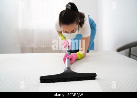 Matratzenreinigung Professional Service von weiblichen Reiniger mit Staubsauger Stockfoto