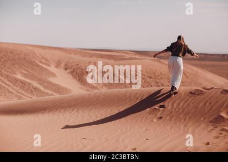 Junge Frau läuft auf Sanddünen in der Wüste Sahara. Stockfoto