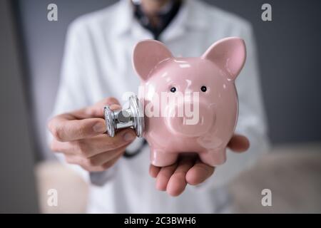 Zugeschnittenes Bild der männlichen Arzt untersuchen Sparschwein mit Stethoskop Stockfoto