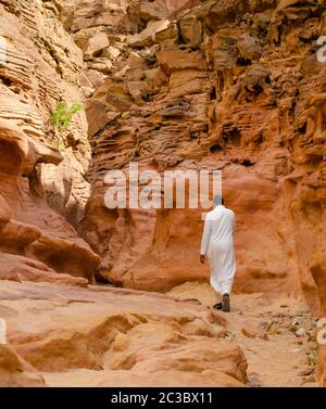 Mann in weißer arabischer Kleidung geht in einem farbigen Canyon in Ägypten Dahab Süd Sinai Stockfoto