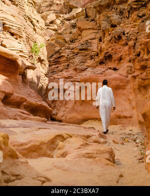 Mann in weißer arabischer Kleidung geht in einem farbigen Canyon in Ägypten Dahab Süd Sinai Stockfoto