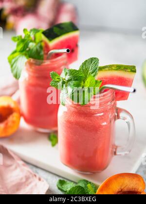 Frisch gekochte Wassermelone und Peach Smoothies in Maurergrug und Metallstroh. Platz für Text oder Design kopieren. Vertikal. Stockfoto