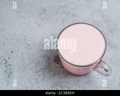 Trendgetränk: pink Latte. Rote Beete oder Himbeeren Cappuccino oder Latte in Glas Schale auf grauzement Hintergrund. Kopieren Sie Platz für Text. Stockfoto