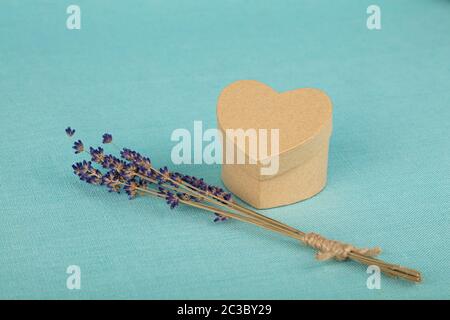 Close up Bukett von getrockneten Lavendelblüten und kleinen herzförmigen Geschenkbox auf Blau Tischdecke, hohe Betrachtungswinkel Stockfoto