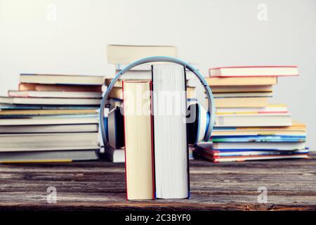 Buch mit Kopfhörer vor Stapel von verschiedenen Büchern auf Holztisch Stockfoto