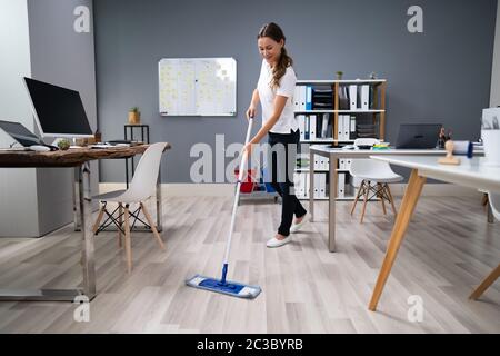 Volle Länge des Weiblichen Hausmeister wischen Stock im Büro Stockfoto