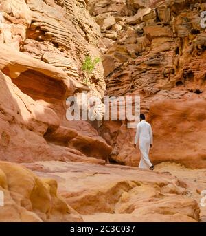 Mann in weißer arabischer Kleidung geht in einem farbigen Canyon in Ägypten Dahab Süd Sinai Stockfoto