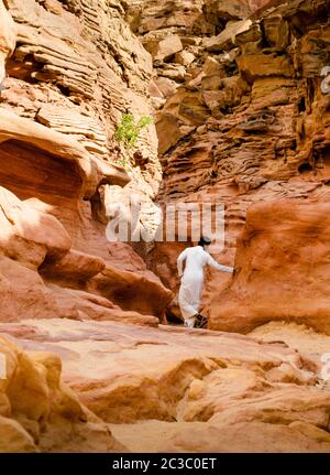 Mann in weißer arabischer Kleidung geht in einem farbigen Canyon in Ägypten Dahab Süd Sinai Stockfoto