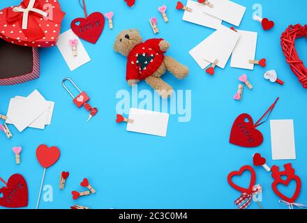 Kartons, die in Form von einem Herz, ein kleiner Teddybär, weiße Leere Visitenkarten mit Wäscheklammern auf einem blauen Hintergrund, Dekor und Objekte für Va Stockfoto