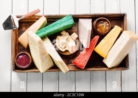 Verschiedene Arten von Käse im Holzkasten serviert. Verschiedene Käsesorten auf weissem Holztisch Stockfoto