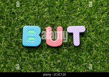 Spielzeug Schaum Buchstaben in Wort, aber auf grünem Gras Hintergrund Stockfoto