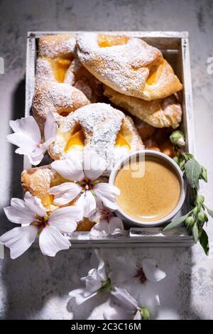 Croissants mit Pfirsich und Kaffee.Süsses Espresso-Frühstück mit Blumen.gesunde Lebensmittel und Getränke. Stockfoto