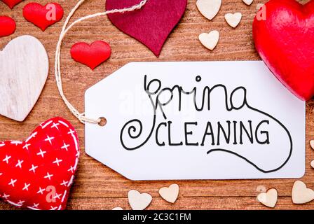 Ein Etikett mit englischen Kalligraphie Frühjahrsputz. Rote Herzen für die Dekoration auf hölzernen Hintergrund Stockfoto