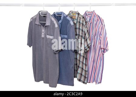 Hängende shirts isoliert. Nahaufnahme der Sammlung von vier männlichen Verschiedenen bunten T-Shirts auf einer Kleiderstange auf einem weißen Hintergrund. Mens Sommer fa Stockfoto