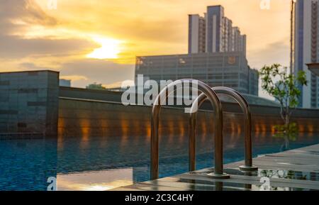 Swimmingpool im Luxushotel und Whirlpool am Morgen mit goldenem Sonnenaufgang. Leiter der Haltegriffe mit sauberem Wasser und Holzboden am SW-Rand Stockfoto