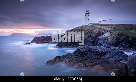 Dämmerung geht bis zur Dämmerung, Sonnenaufgang am Fanad Head Leuchtturm mit verschwommenem Wasser des Atlantischen Ozeans Stockfoto