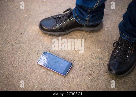 Person Kommissionierung gebrochen Smartphone geknackt Bildschirm auf dem Boden Stockfoto