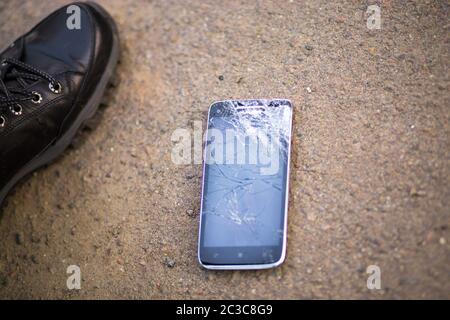 Person Kommissionierung gebrochen Smartphone geknackt Bildschirm auf dem Boden Stockfoto
