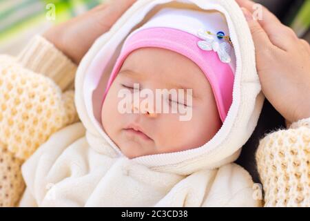 Porträt eines zwei Monate alten Babys, das auf den Füßen der Mutter in einem Park schläft Stockfoto