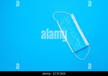 Blaue sterile medizinische Maske mit weißen elastischen Bändern für Ärzte auf hellblauem Hintergrund, flacher Lay, Kopierraum Stockfoto